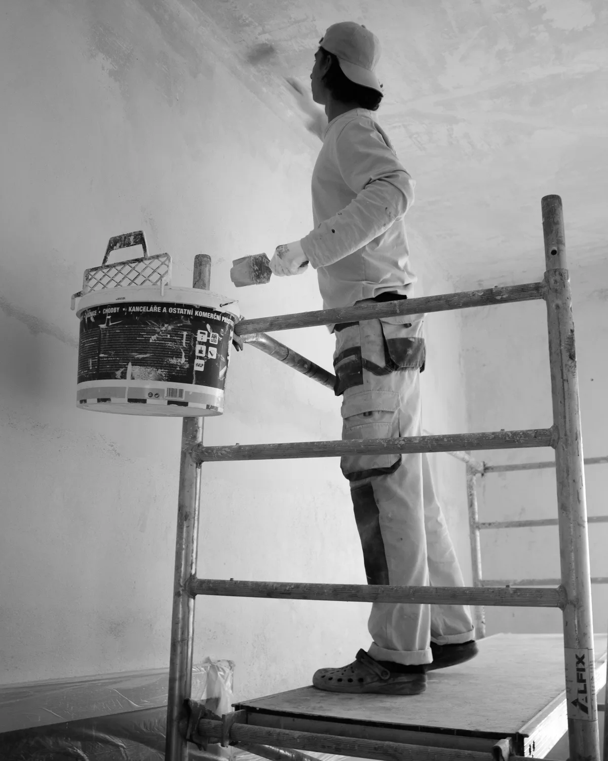 Maler arbeitet mit Pinsel an einer frisch gestrichenen Wand